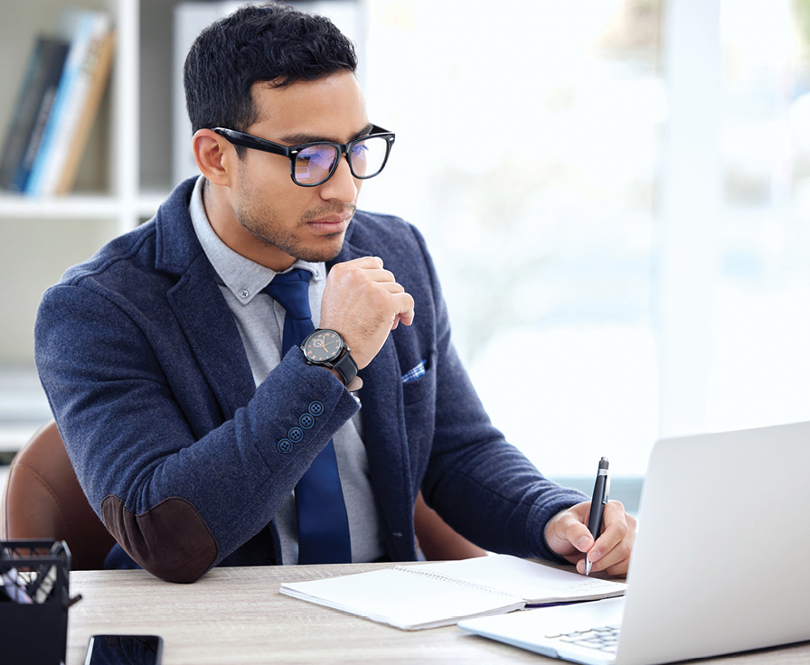 Business man wearing glasses studies information on his laptop