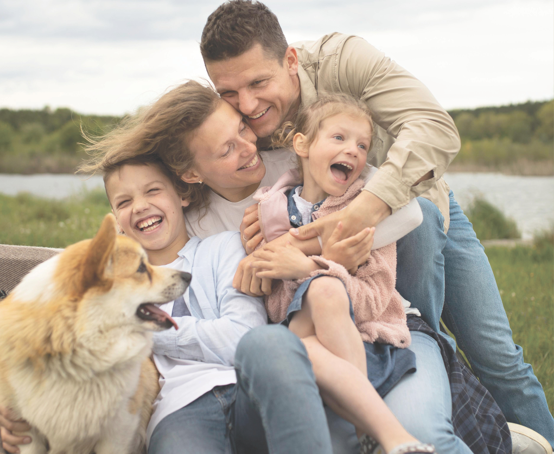 Family hugging outdoors with a dog